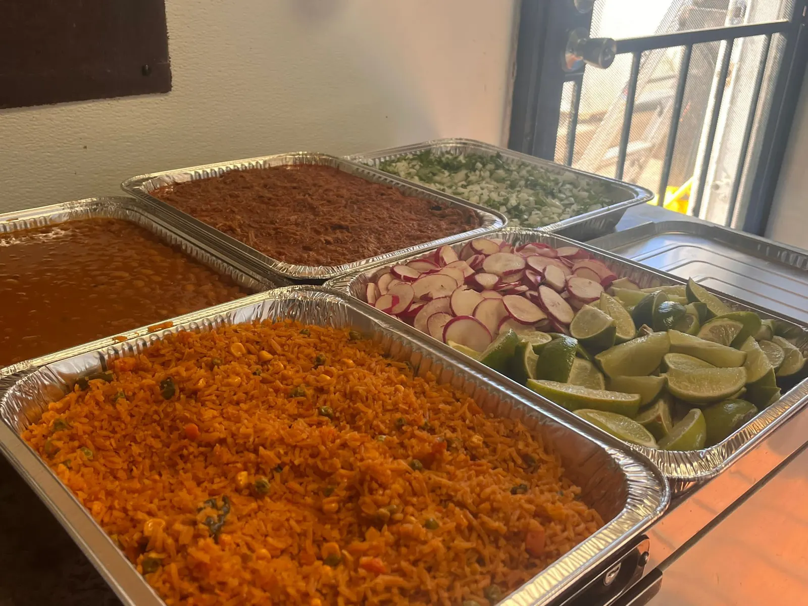 Mr. Birria catering food spread with trays of birria, rice and beans