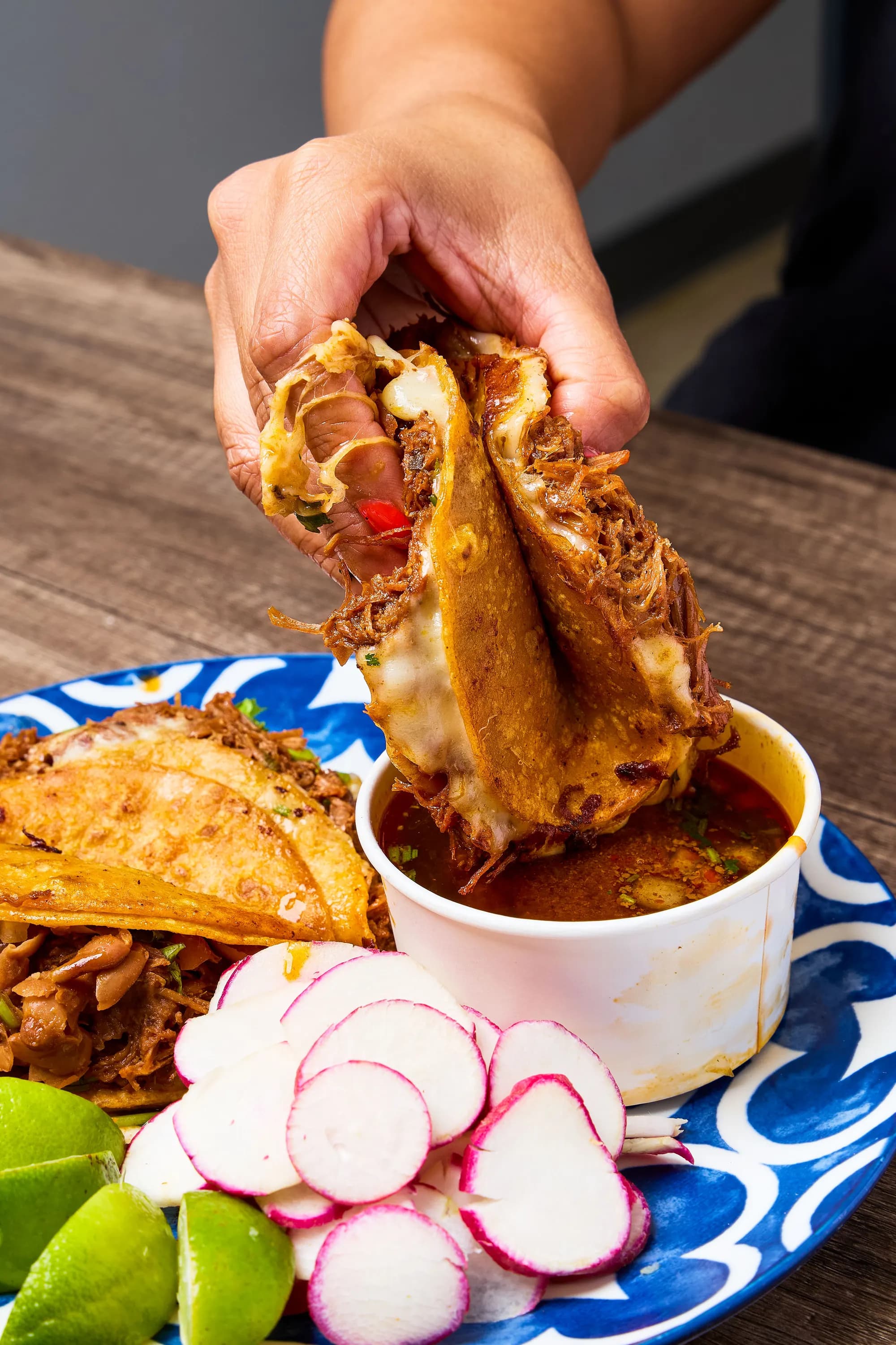 Birria taco dipped into rich consommé — action shot